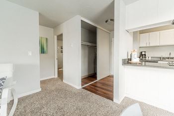 A renovated living room with a kitchen and an open door to a bedroom